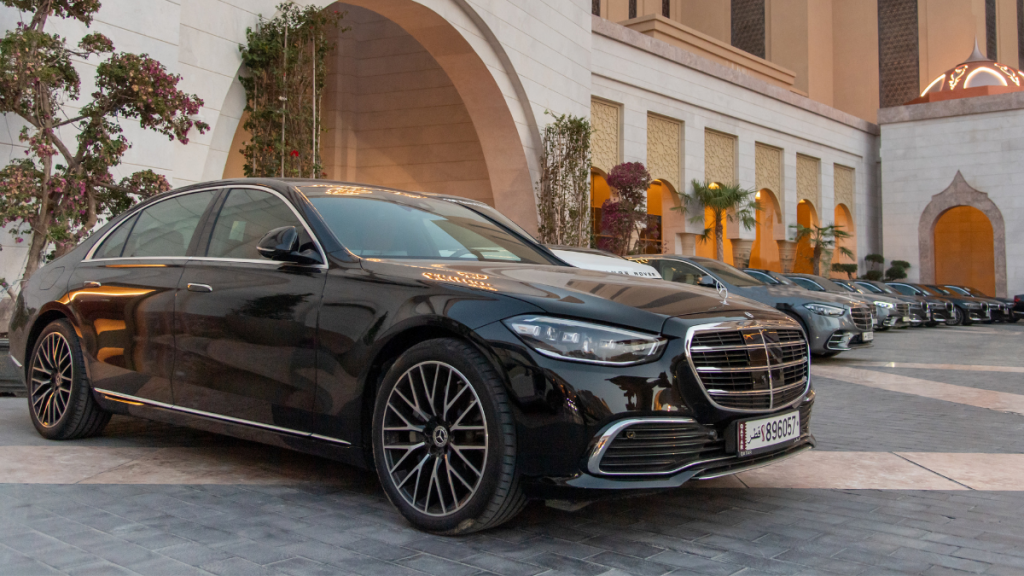 Front view of black Mercedes-Benz S-Class and fleet of ROLZO cars parked in front of St Regis Hotel in Doha